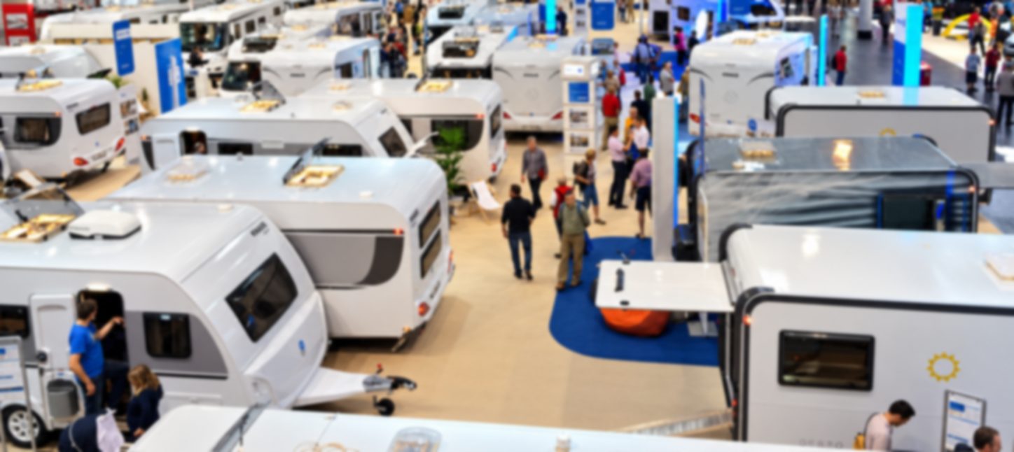 Messehalle voller Besucher Besucher zwischen Wohnwagen in einer vollen Messehalle